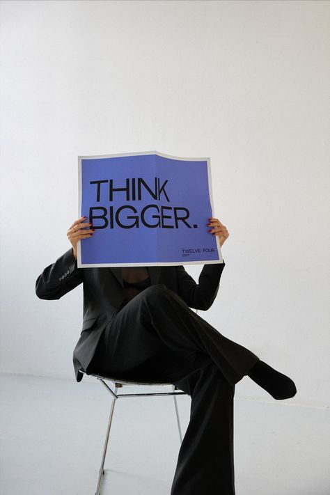 person reading blue newspaper, on which the fist page says "think bigger"